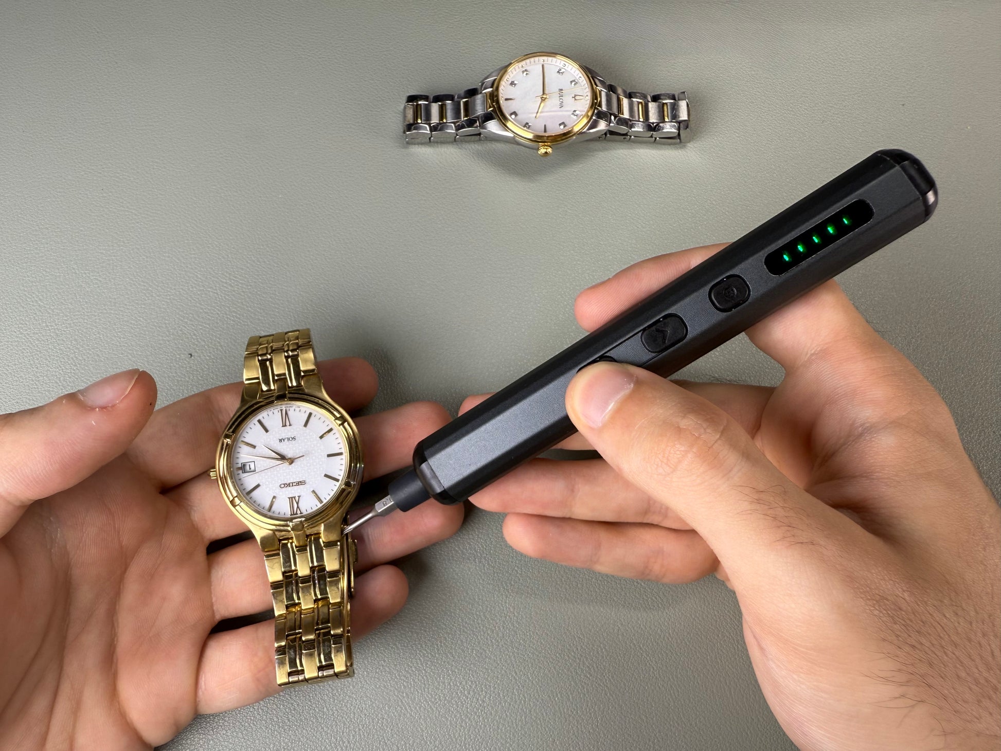 An electric screwdriver adjusting the link of a gold wristwatch, showcasing fine detail work on delicate accessories with ease and efficiency.